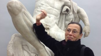 photo of woman holding arm up in front of naked cupid statue